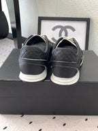 Black unisex Chanel sneakers, heel view with white sole and logo detailing