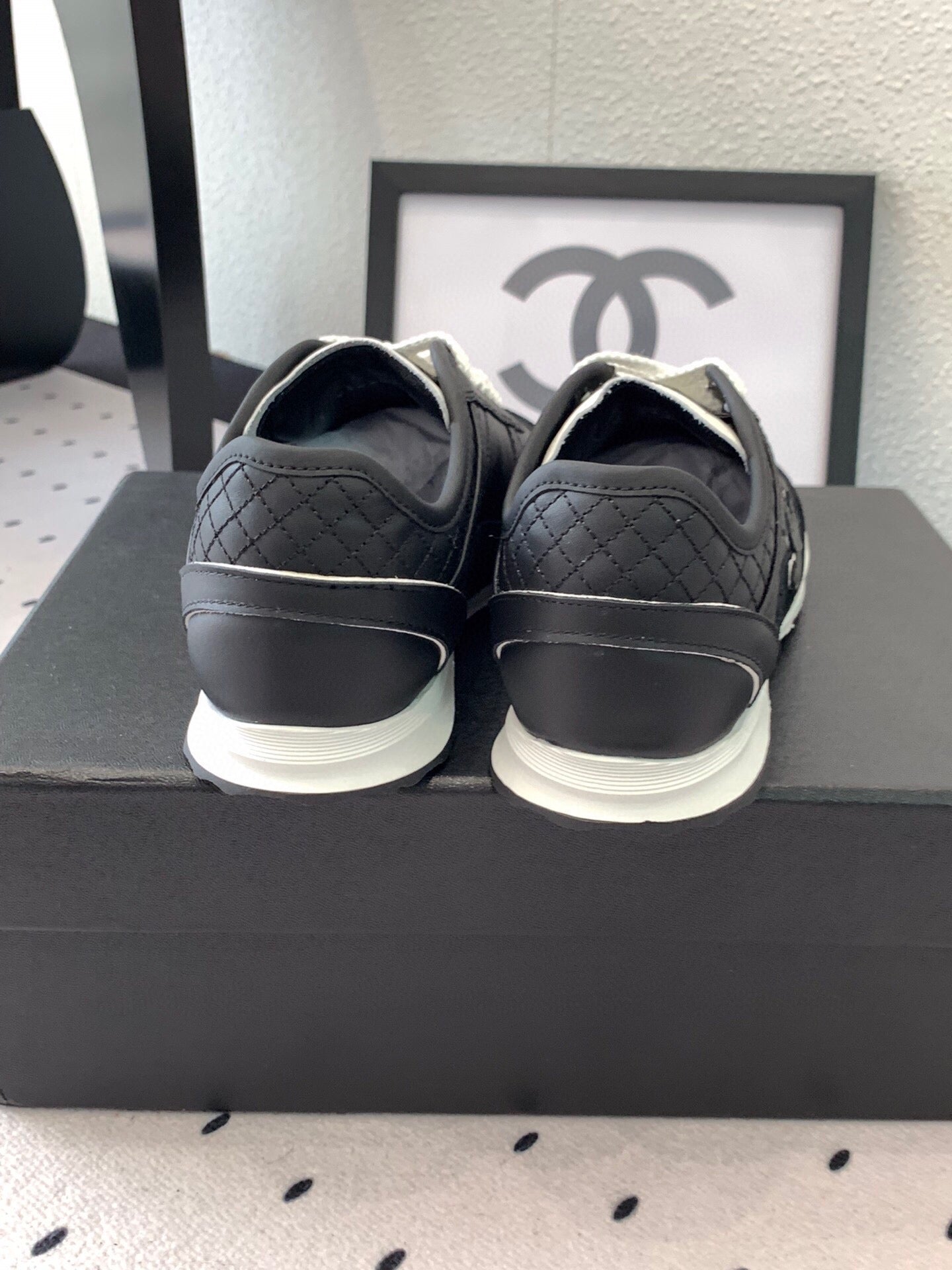 Black unisex Chanel sneakers, heel view with white sole and logo detailing