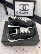 Black unisex Chanel sneakers on black box, top view with white laces