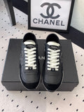 Black unisex Chanel sneakers with white laces and CC logo on the tongue
