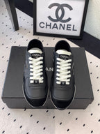 Black unisex Chanel sneakers with white laces and CC logo on the tongue