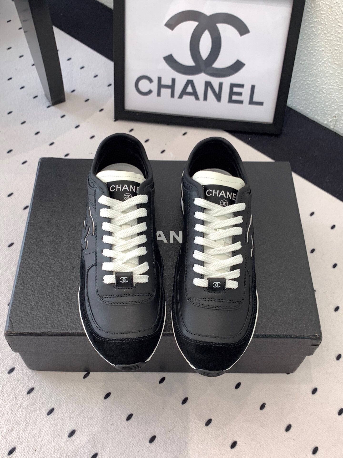 Black unisex Chanel sneakers with white laces and CC logo on the tongue