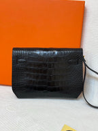 Hermes croc-embossed rectangular flap bag with side pull tabs and dark strap.