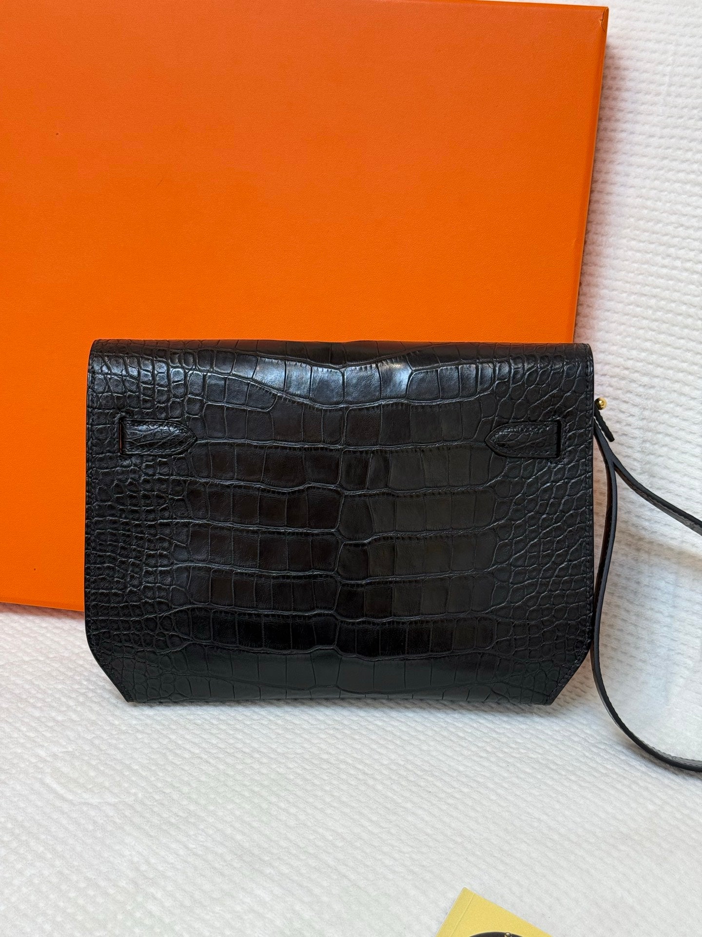 Hermes croc-embossed rectangular flap bag with side pull tabs and dark strap.