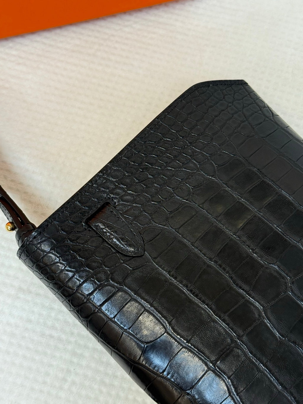 Hermes croc-embossed leather flap bag texture close-up with stitched seam.