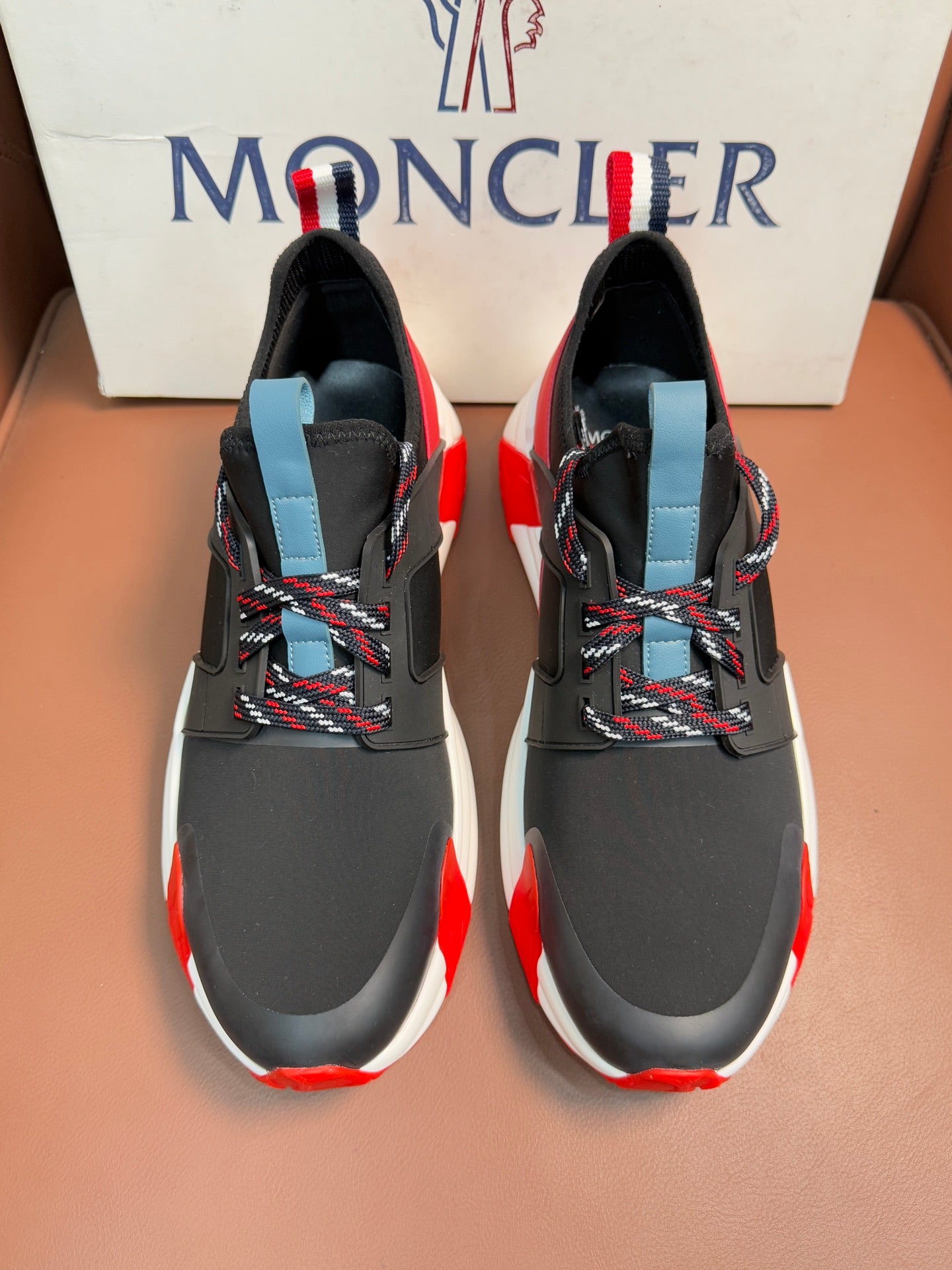 Moncler luxury shoes with black upper, red side accents, and light blue heel pull tab