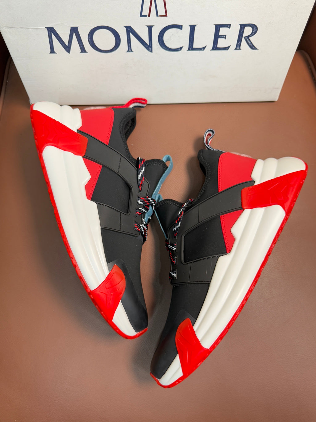 Moncler luxury shoes with black upper, red collar, and white cushioned sole