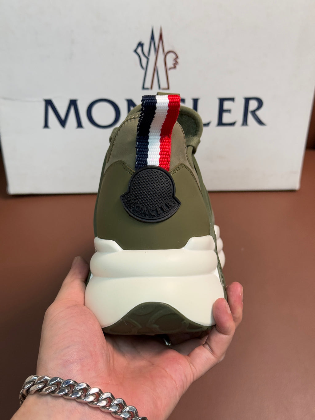 Moncler luxury sneakers with olive green mesh, striped back panel, and cushioned heel
