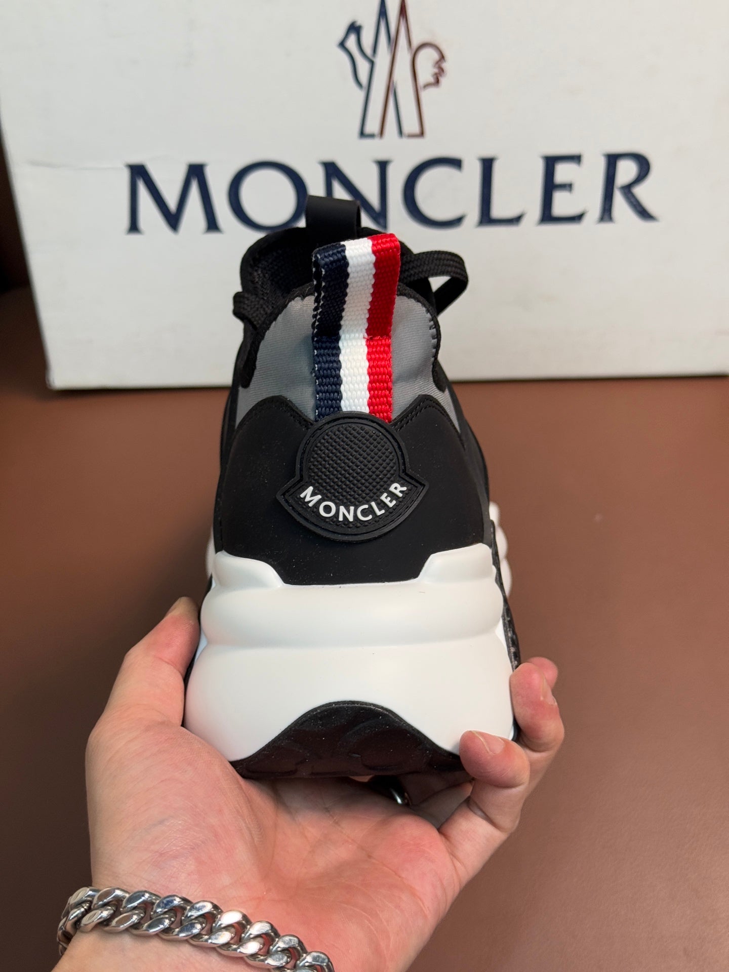 Moncler sneakers heel view with red and blue striped strap and logo tab