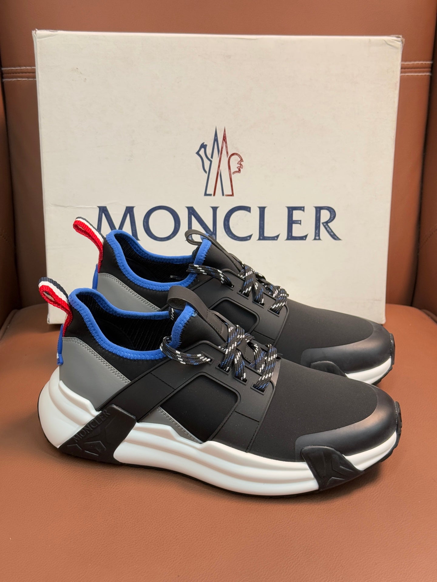 Moncler dark sneakers with blue collar, red/white pull-tab, white sculpted sole