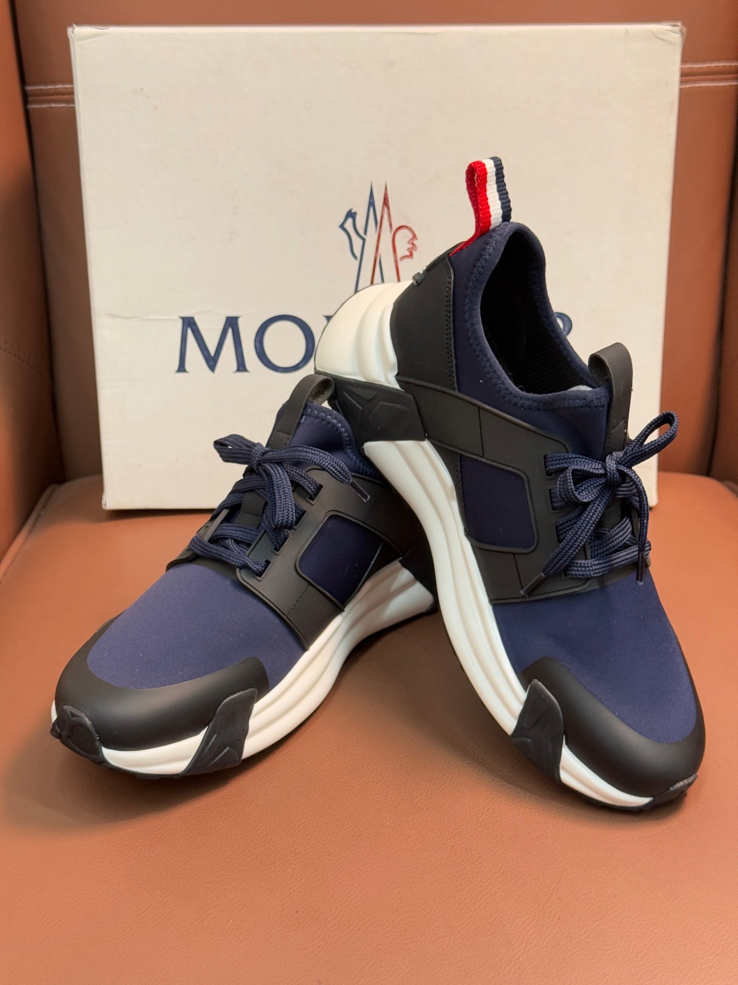Luxury sneakers with dark navy uppers, lace-up front, red-white-blue heel stripe detail