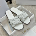 White Dior slide sandals with wide cross strap and dark edge sole