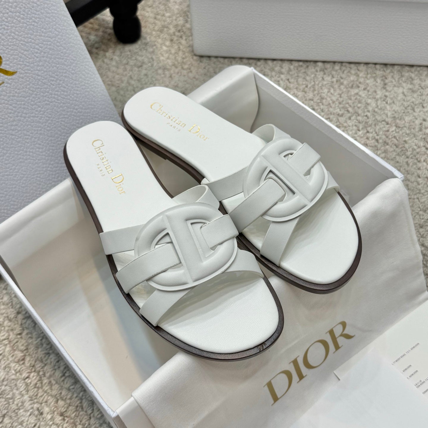 White Dior slide sandals with wide cross strap and dark edge sole