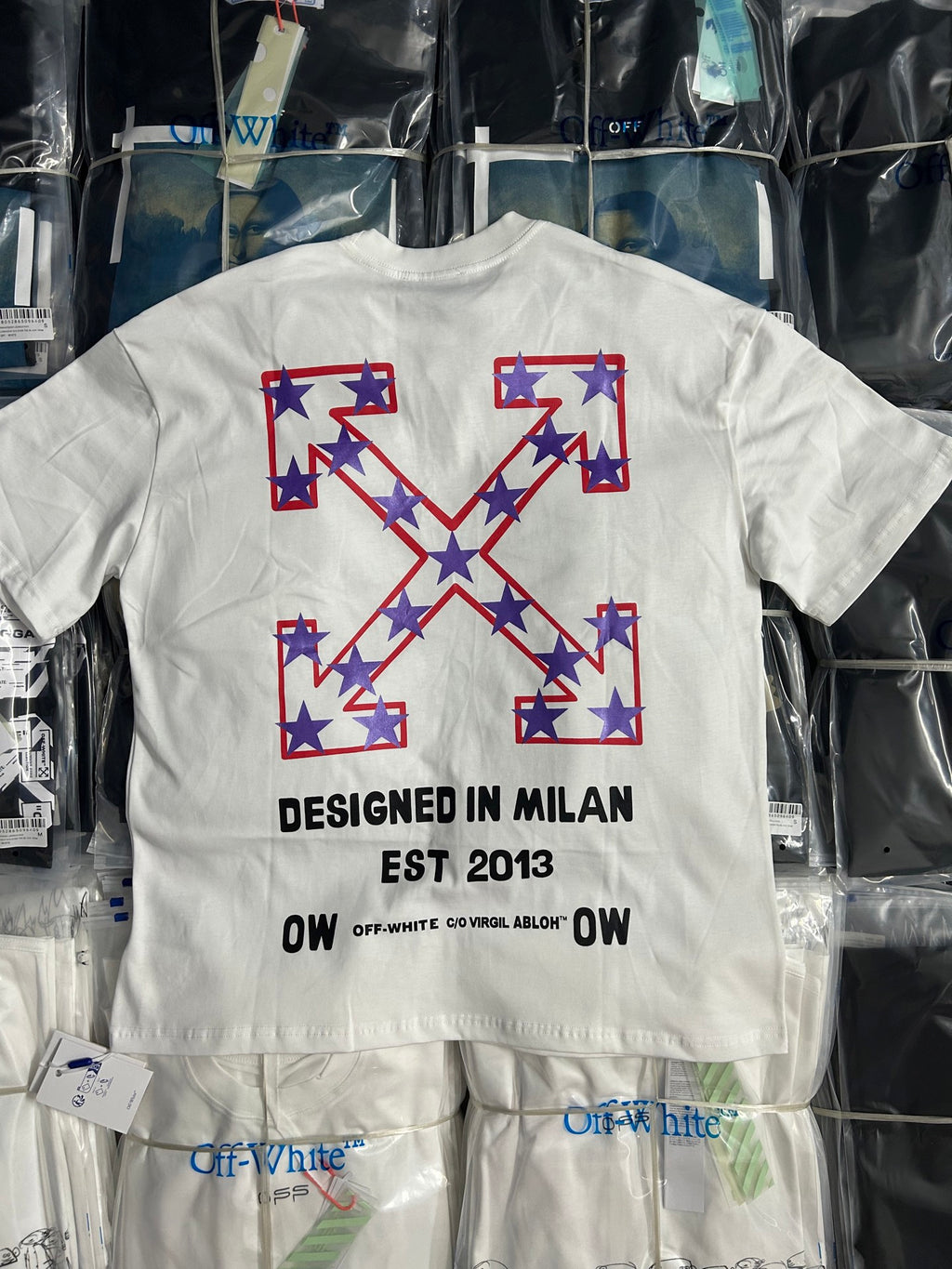 Off-White white T-shirt with large blue star X graphic and text "DESIGNED IN MILAN"