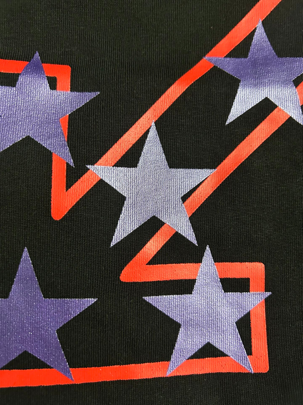 Black T-shirt graphic close-up of purple stars around red outlined shape