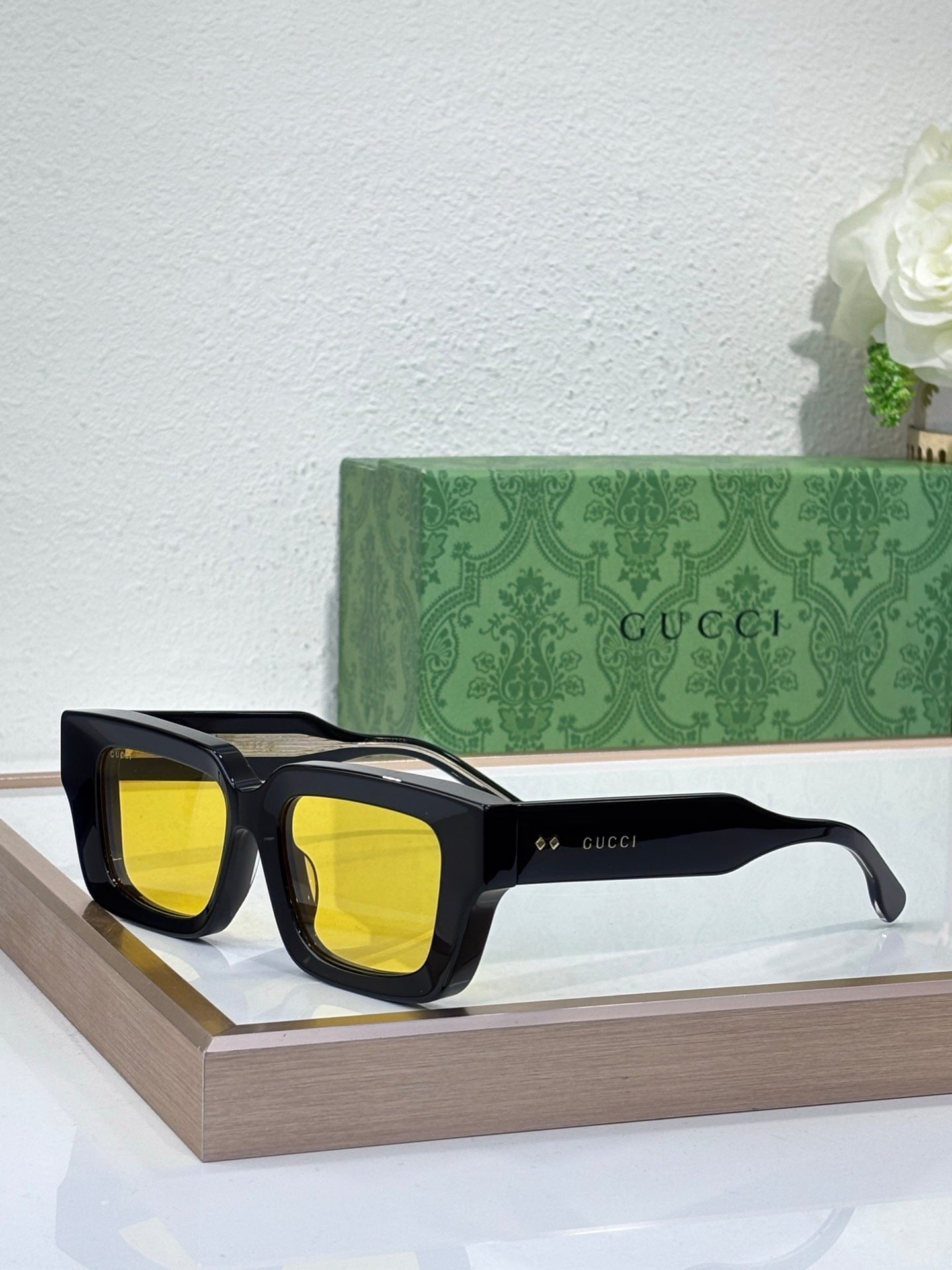 Gucci sunglasses with black frames and yellow tinted lenses, rectangular shape