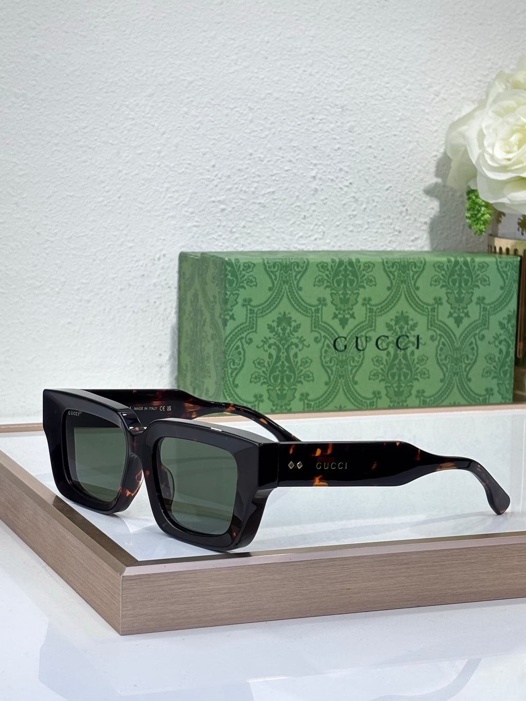 Gucci sunglasses with black frames and green tinted lenses, rectangular shape