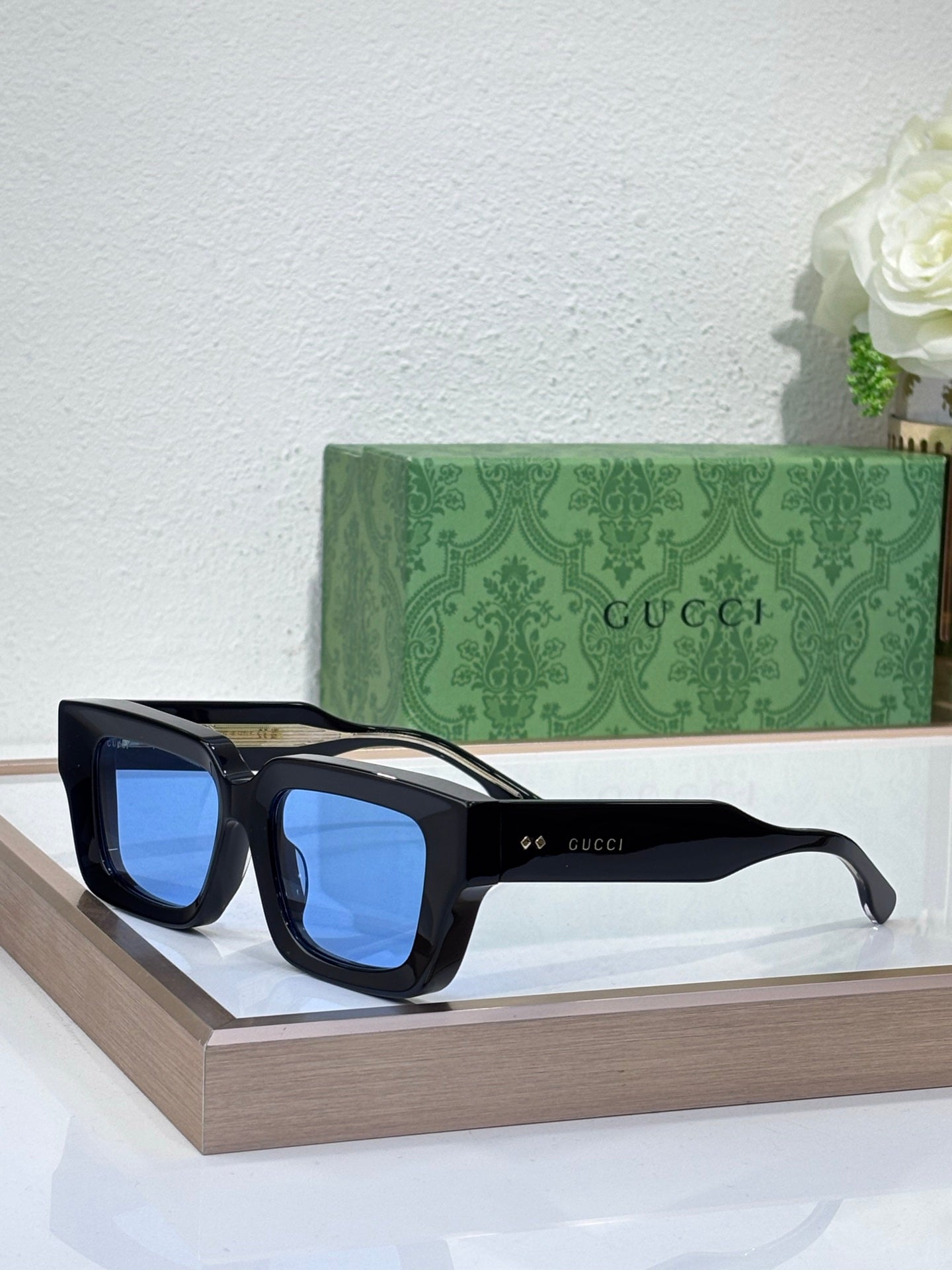 Gucci sunglasses with black frames and blue tinted lenses, rectangular shape
