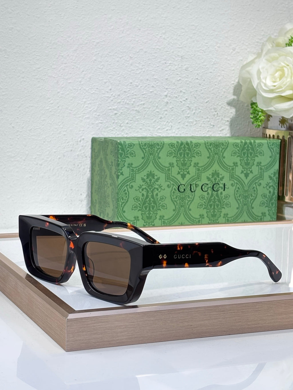 Gucci sunglasses with black frames and warm brown tinted lenses, rectangular shape
