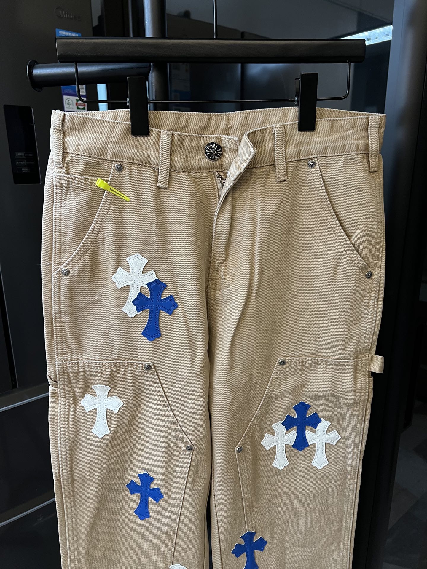 Khaki pants with blue and white cross patches, zip front and belt loops