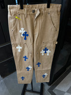 Beige denim pants with embroidered cross patches and buttoned waistband