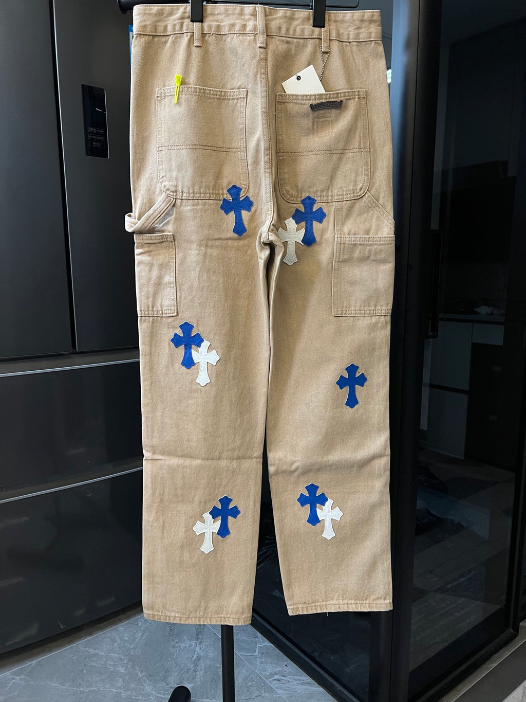Khaki cargo pants with multiple blue cross patches and side pockets
