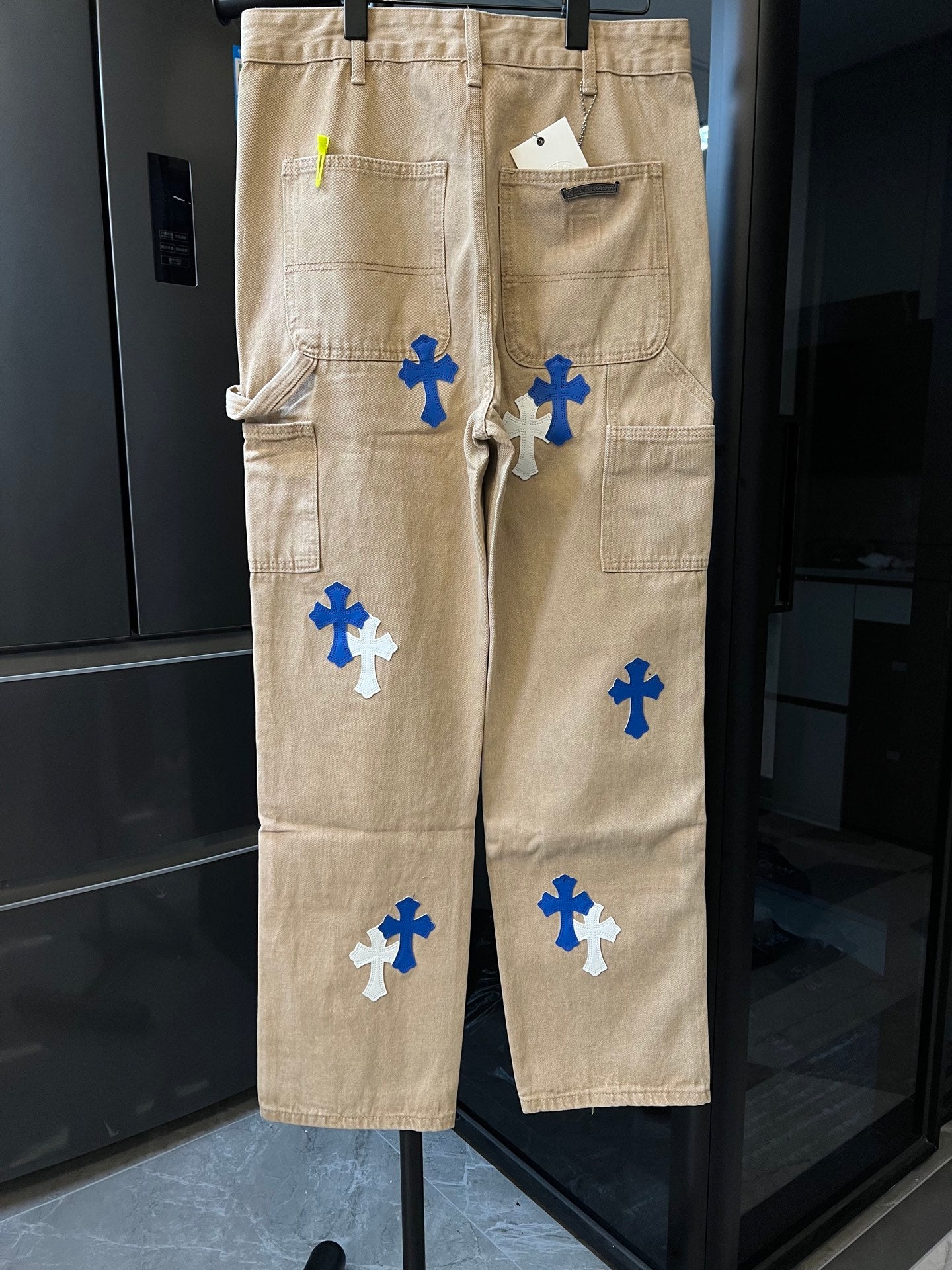 Khaki cargo pants with multiple blue cross patches and side pockets