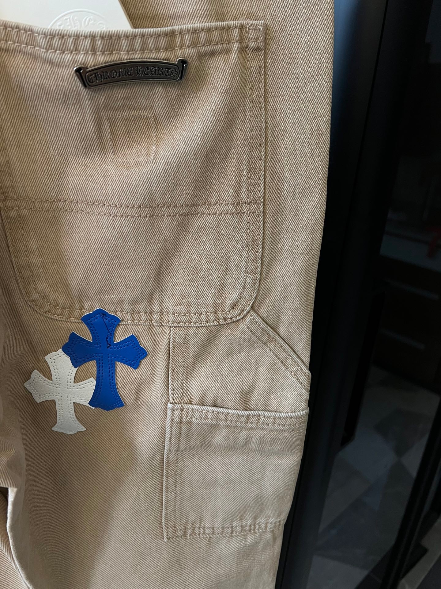 Khaki cargo pants with blue cross patch and front flap pocket detail