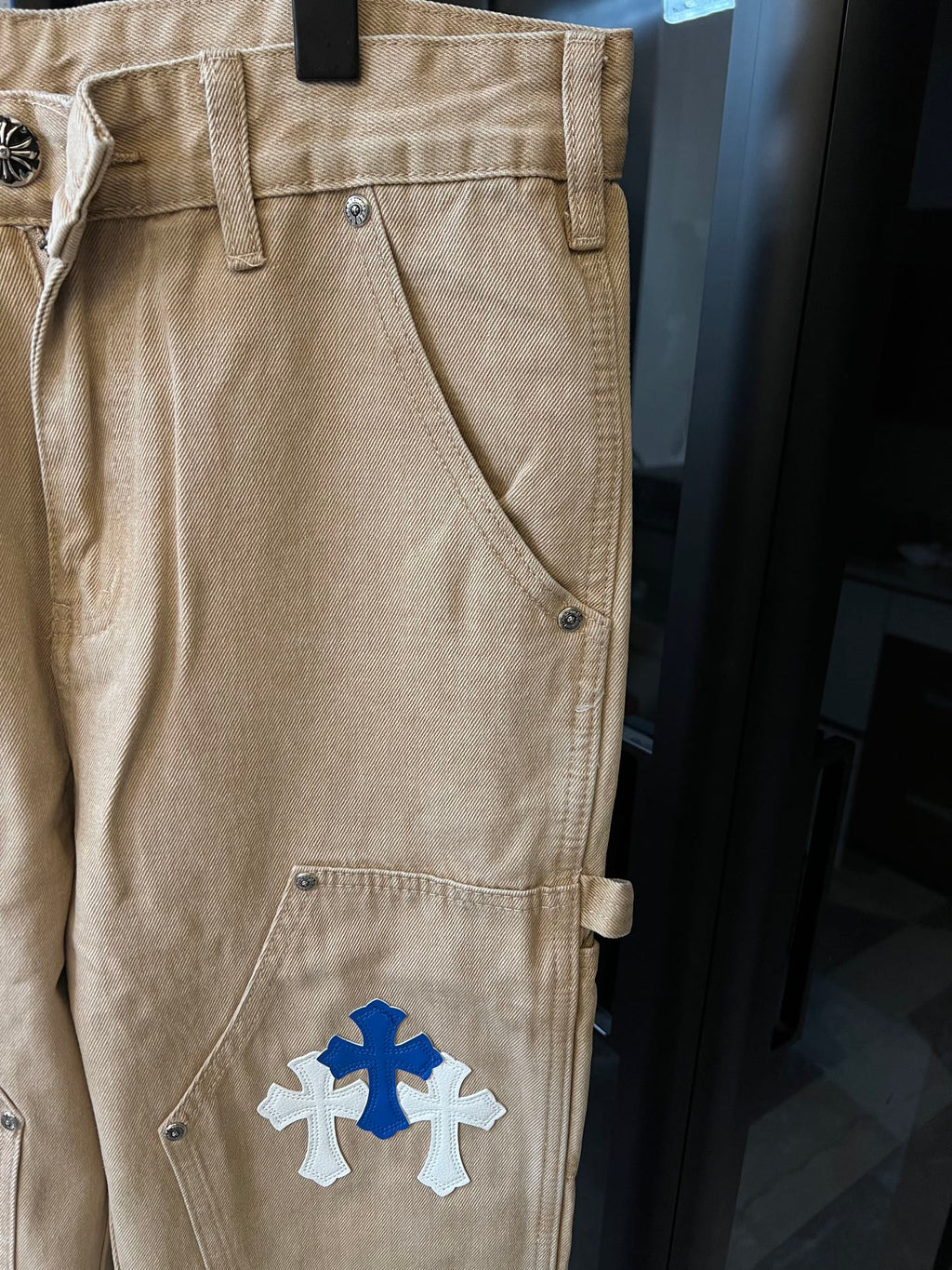 Khaki pants with blue cross and white cross patches, front side pocket detail