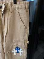 Khaki pants with blue cross and white cross patches, front side pocket detail