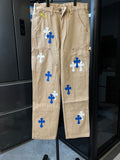 Beige denim cargo pants with blue and white cross patches, front view