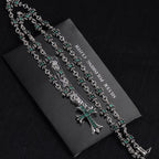 Silver chain necklace with cross charm and repeating teal-green flower links