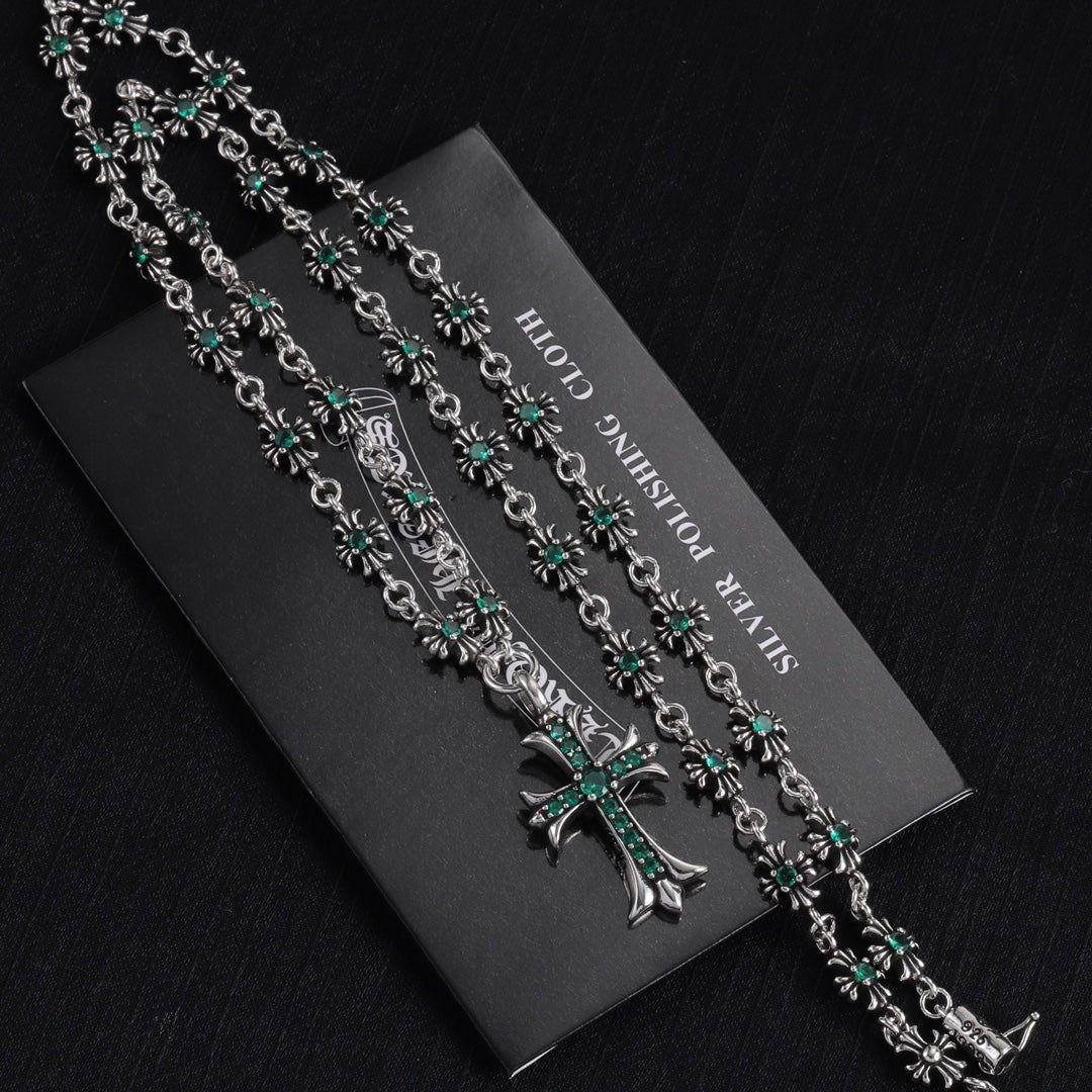 Silver chain necklace with cross charm and repeating teal-green flower links