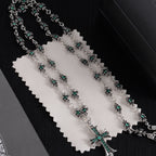 Silver chain necklace with teal-green flower bead details and cross centerpiece