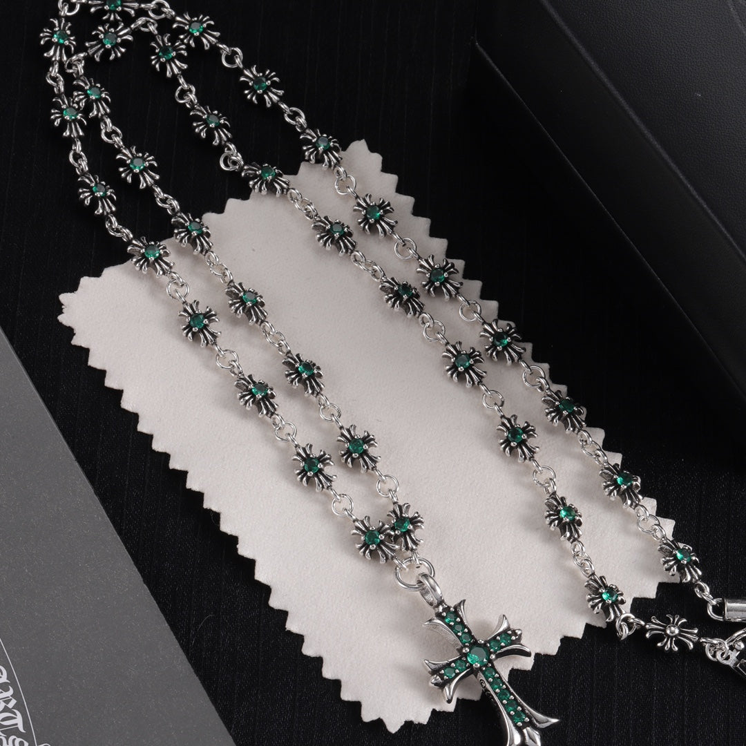 Silver chain necklace with teal-green flower bead details and cross centerpiece