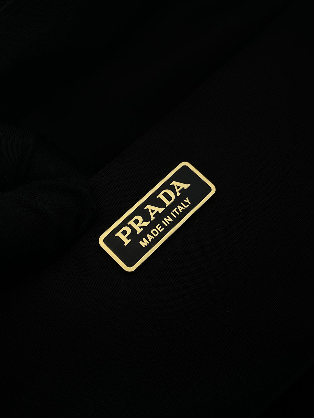 Prada nylon label patch reading 'Made in Italy' on dark fabric