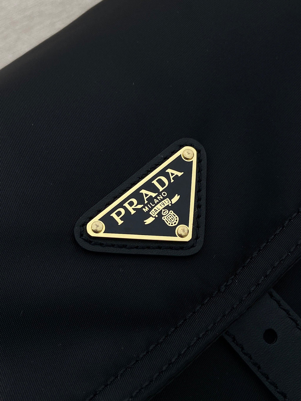 Prada logo plaque on dark navy nylon flap with gold trim and stitching