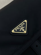 Prada logo plaque on dark navy nylon flap with gold trim and stitching