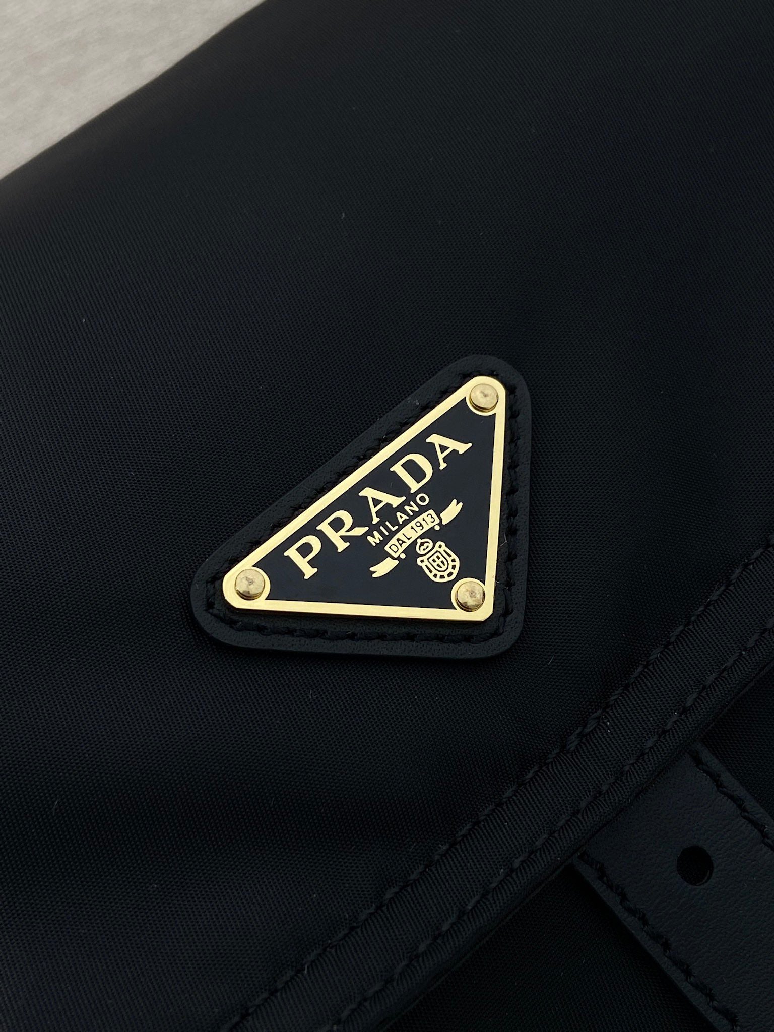 Prada logo plaque on dark navy nylon flap with gold trim and stitching