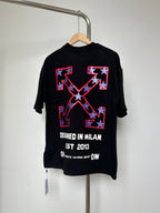Off-White dark graphic T-shirt with large red-and-blue emblem and “DESIGNED IN MILAN” text.