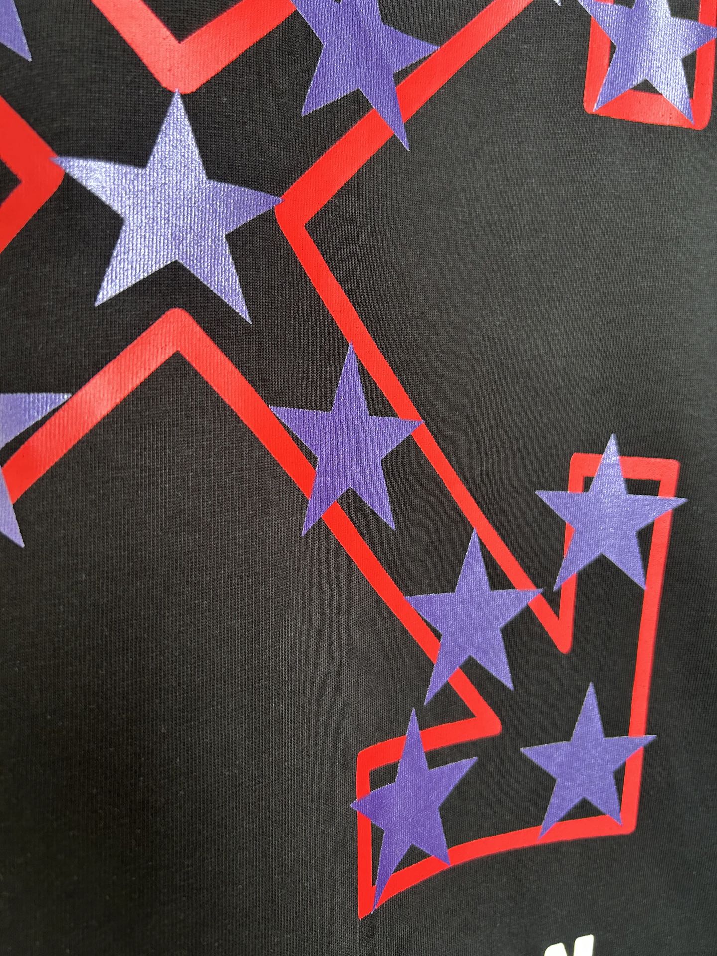 Off-White dark T-shirt close-up of purple stars with red outline graphic.