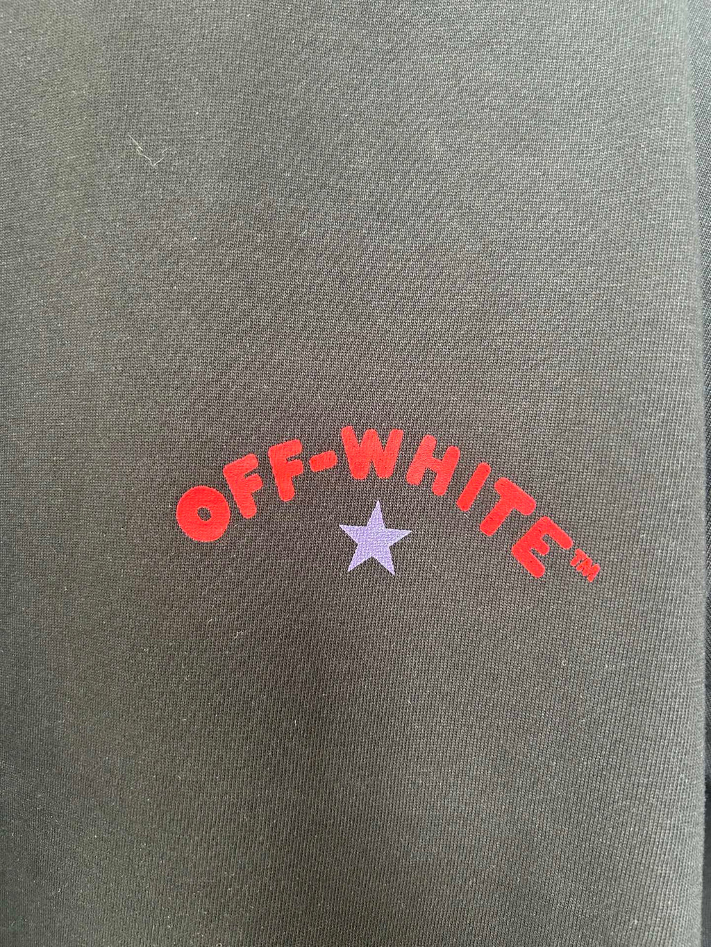 Off-White logo print on dark fabric: red “OFF-WHITE” text with purple star.