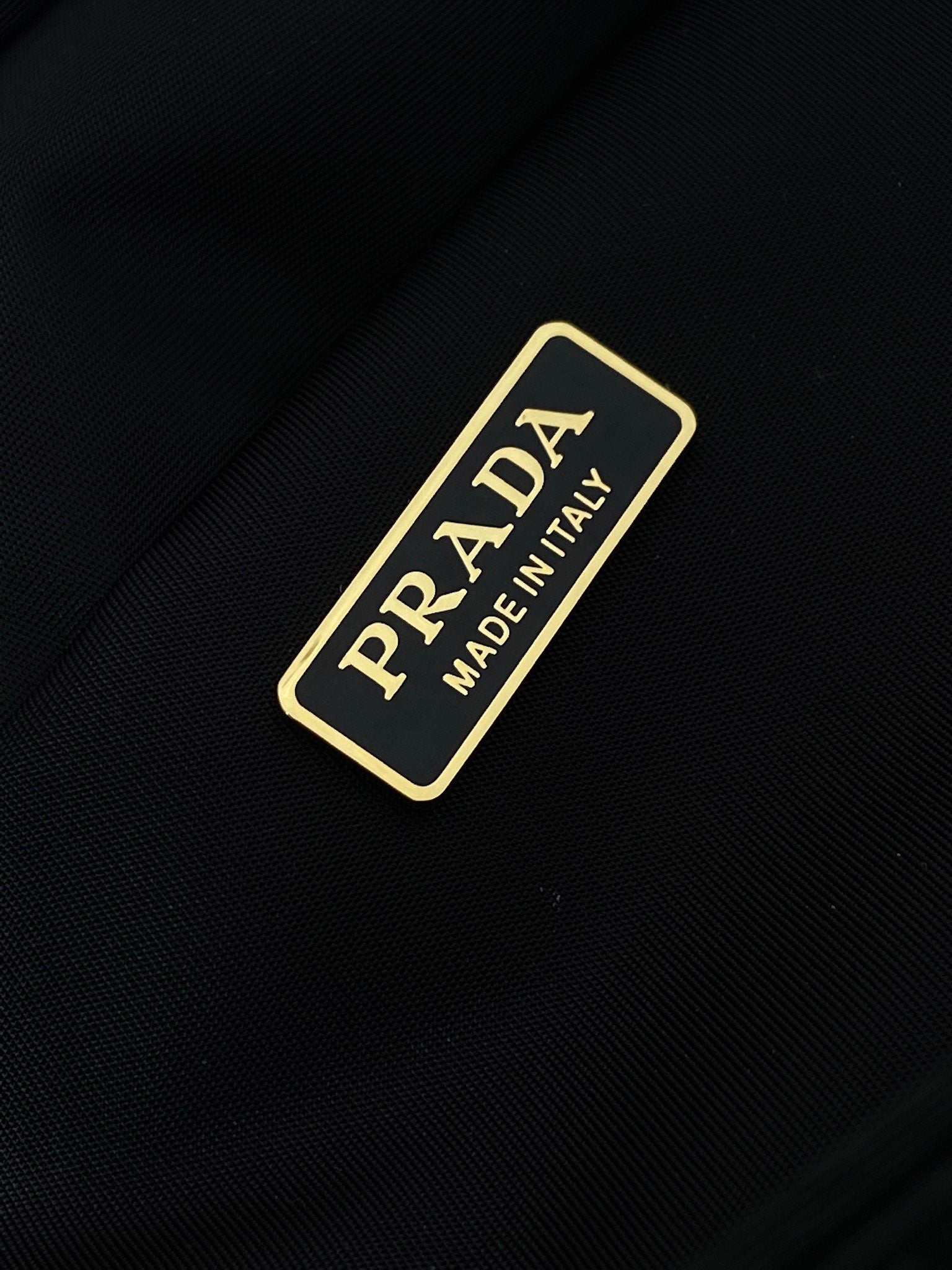 Prada made in Italy label on dark navy fabric with gold border