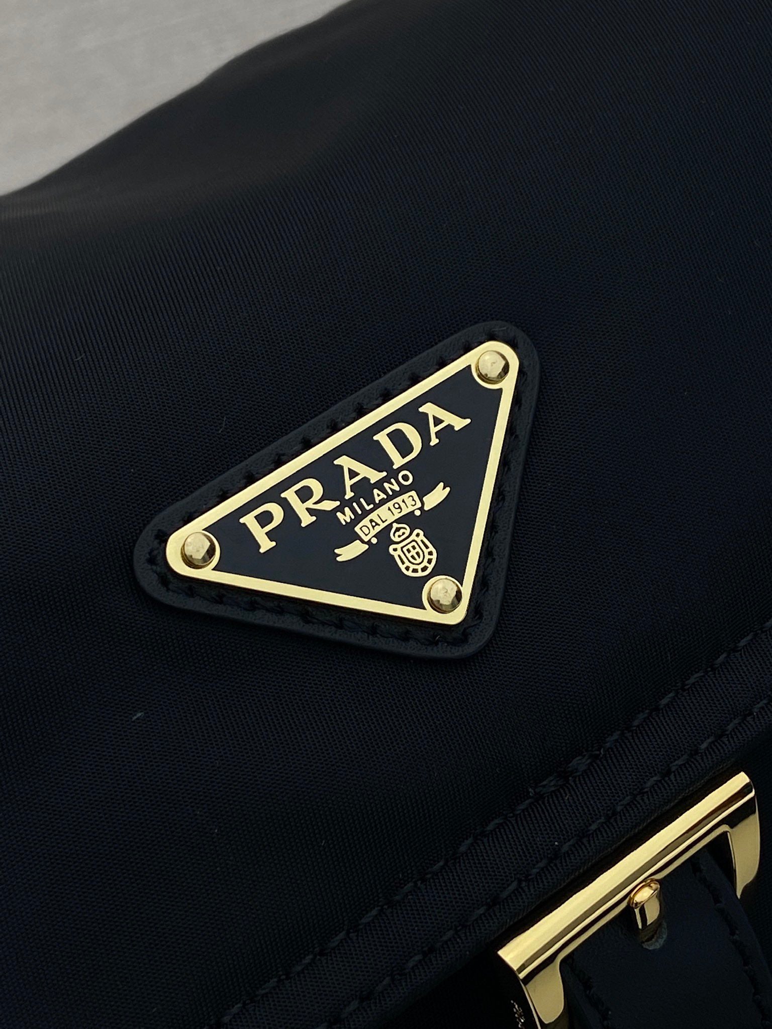 Prada logo plaque on dark navy crossbody flap with gold trim