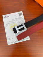 Reversible leather belt showing dark strap and red underside with H buckle