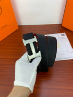 Hermes reversible belt with black outer and red underside, silver buckle shown in hand