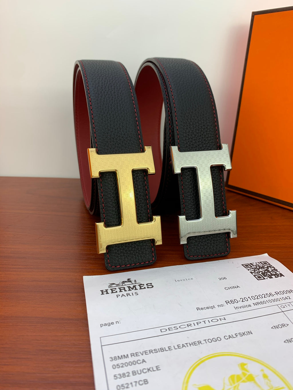 Black leather belt with H buckle, gold and silver finishes shown upright.