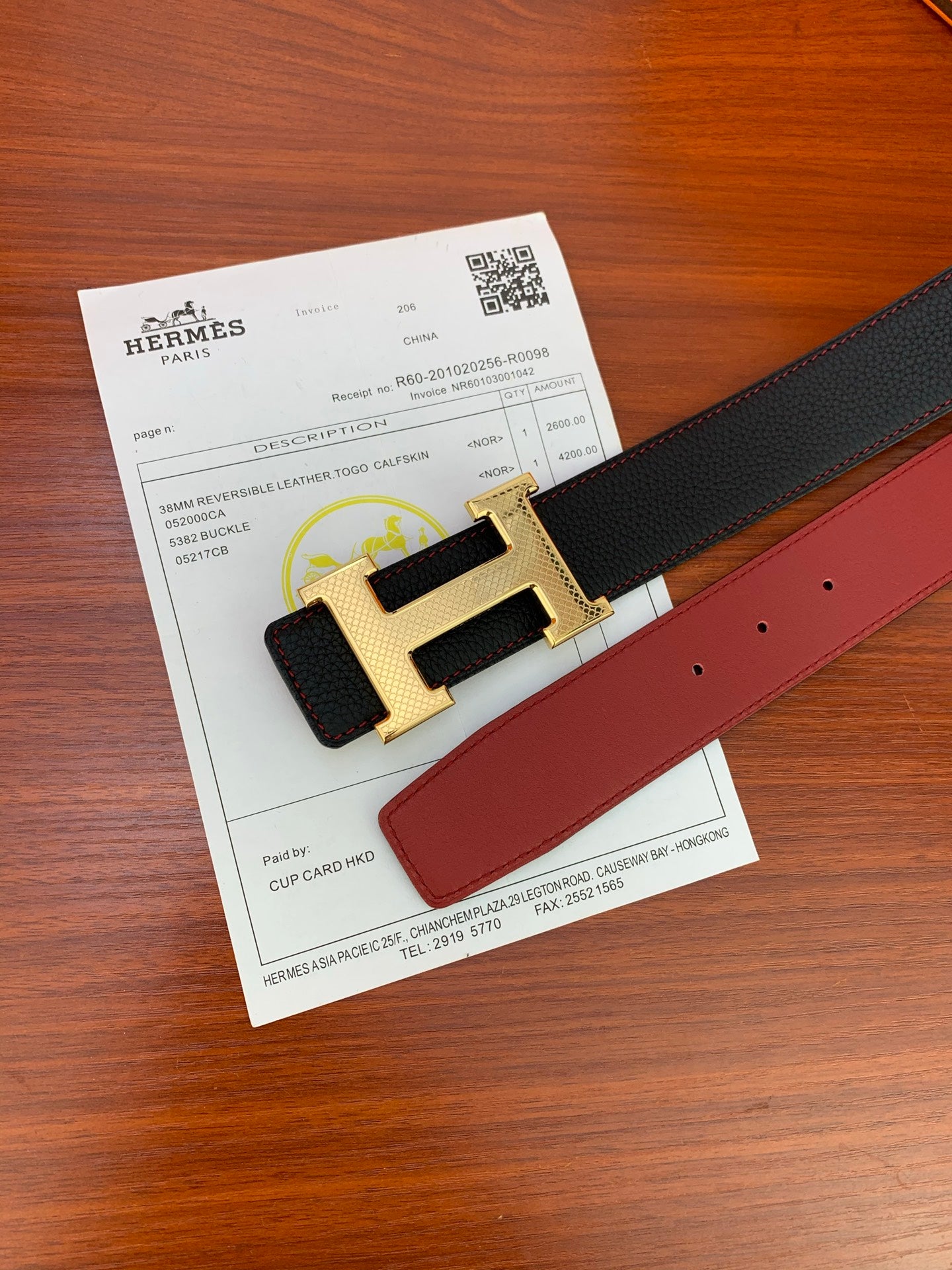 Reversible leather belt with black strap and gold-tone H buckle, red reverse leather