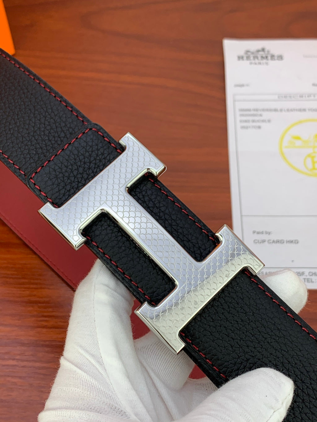 Reversible leather belt with black strap, red stitching, and silver-tone H buckle