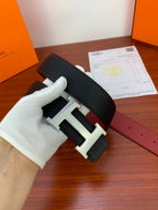 Leather belt with black textured strap and silver-tone H buckle, showing red underside